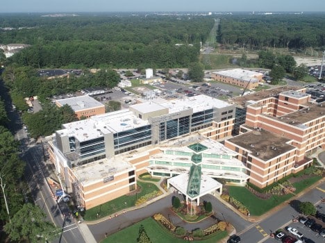 A large brick hospital building with a glass and white entrance.