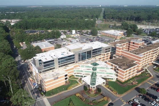 A large brick hospital building with a glass and white entrance.