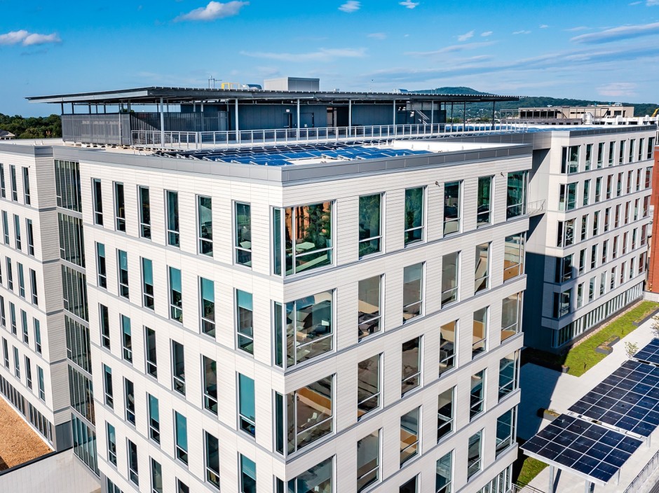 A white building with many windows, and solar panels on the roof.