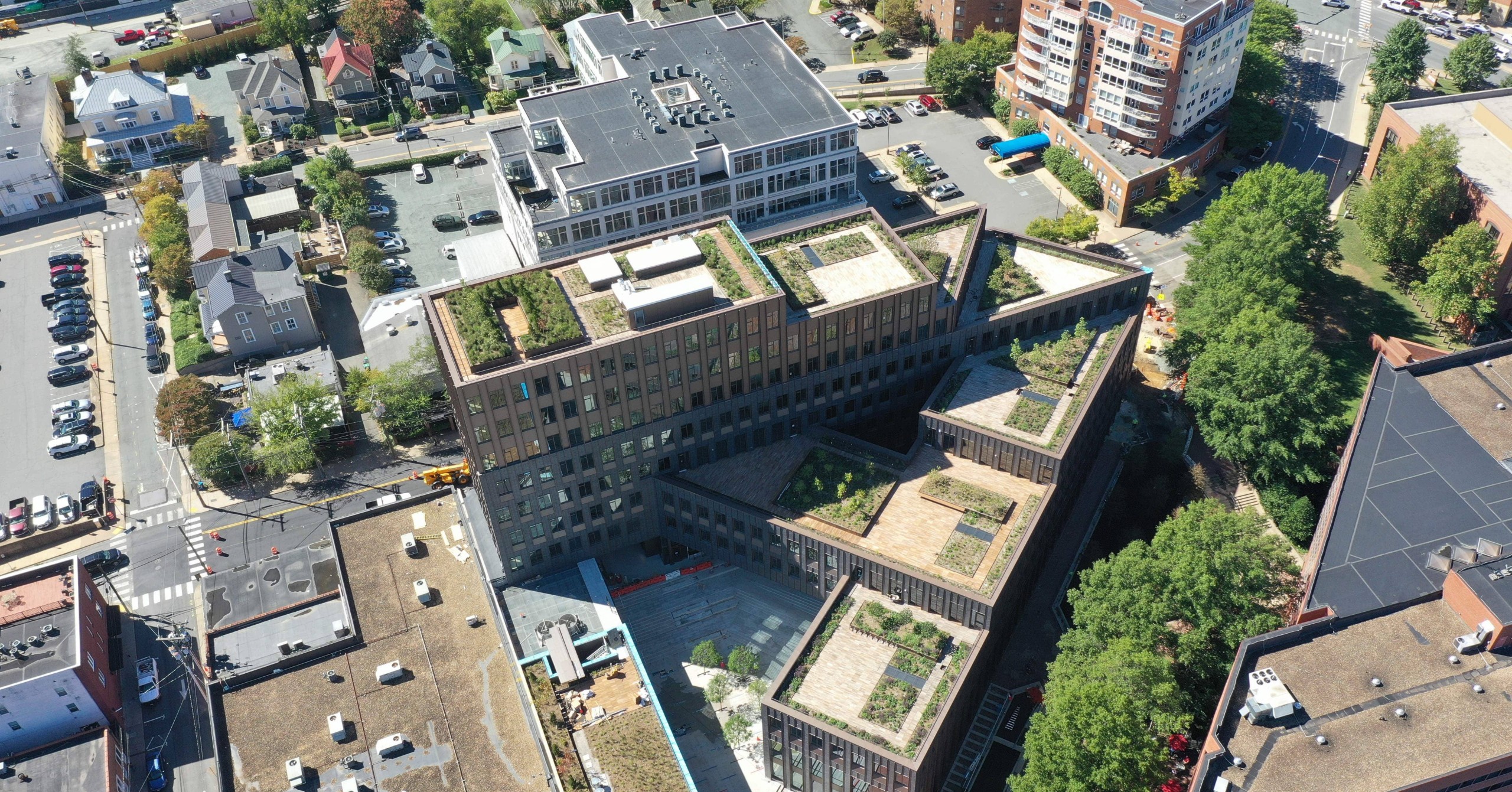 An aerial view of a brick office building with tiered levels and rooftop gardens.
