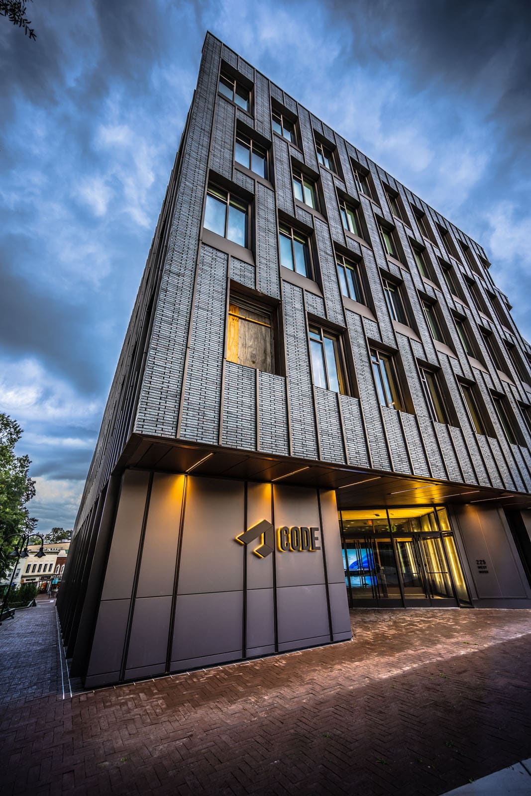 A grey brick building with a geomatic facade. Sign on the building says ' CODE"