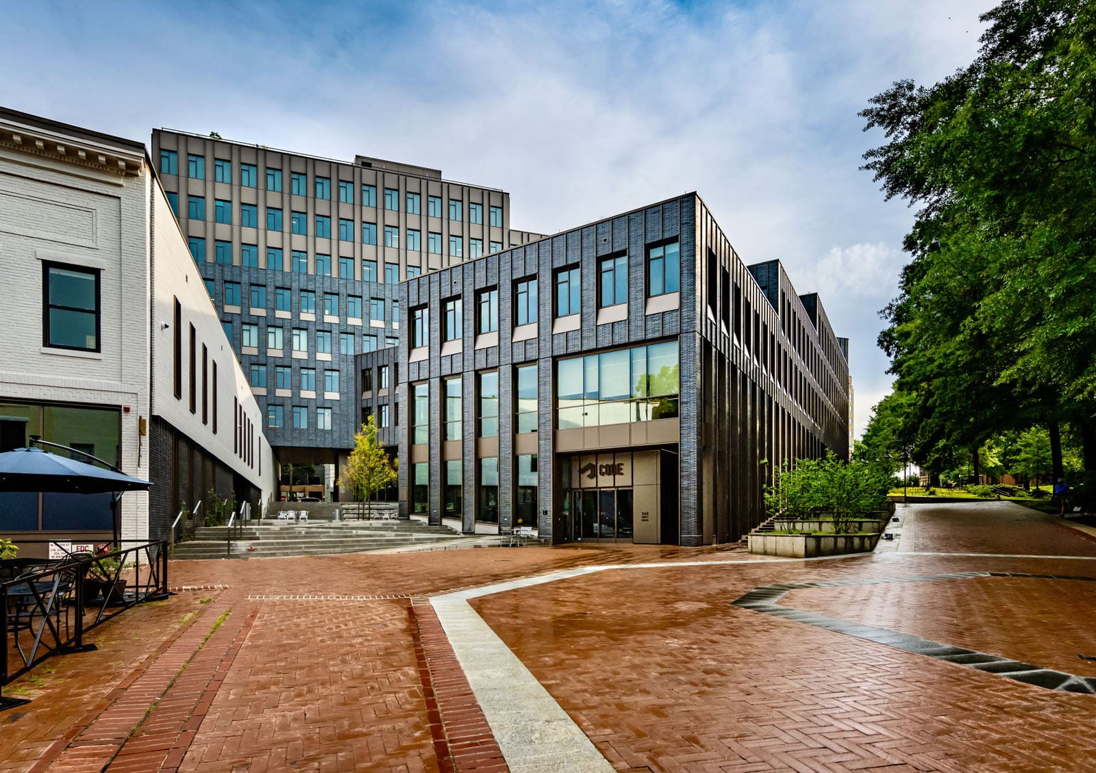 A modern building with a brick and glass facade and the word “CODE” above the entrance, surrounded by a cloudy sky.