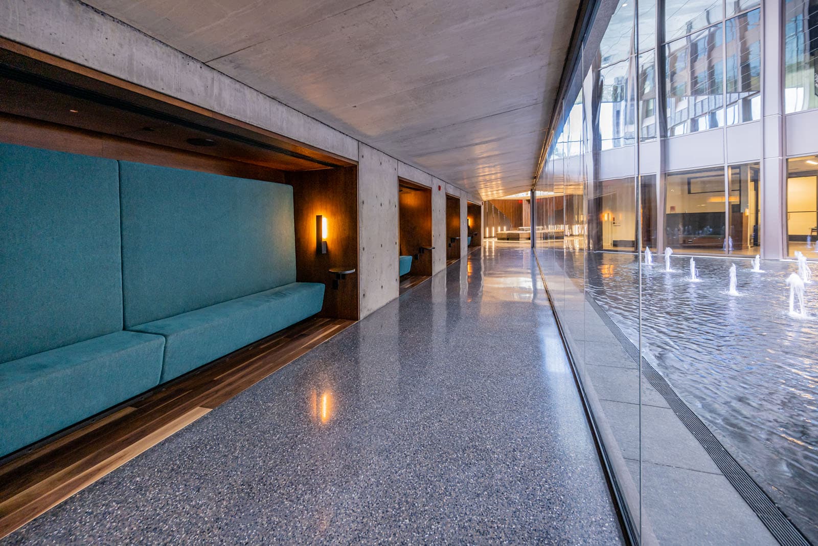 Wooden built in seating with teal cushions facing a large window overlooking a fountain.