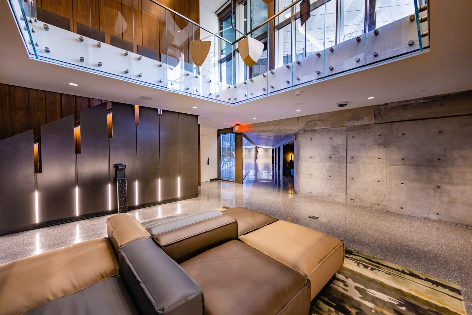 A lobby area with high ceilings, concrete walls and wood and steel accents.