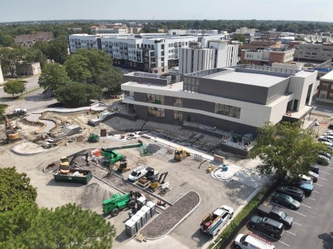 Aerial view of Chrysler Museum. Gray building with large parking lot of gravel with construction equipment parked.