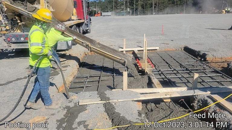 Men pouring concrete into site pad