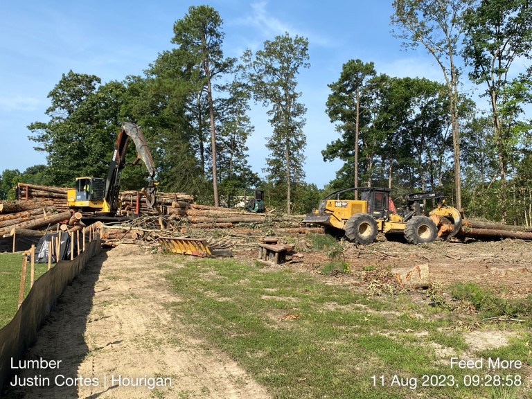 bobcats and backhoe moving timber from jobsite